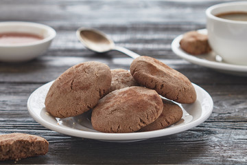 Homemade biscuits of buckwheat flour with honey on a plate and a cup of coffee on a wooden background.