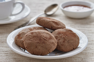 Homemade biscuits of buckwheat flour with honey on a plate and a cup of coffee on a wooden background.