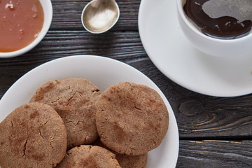 Homemade biscuits of buckwheat flour with honey on a plate and a cup of coffee on a wooden background.