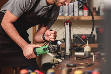 cropped shot of young worker cutting metal with angle grinder in workshop