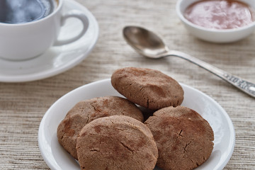 Homemade biscuits of buckwheat flour with honey on a plate and a cup of coffee on a wooden background.