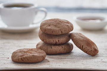 Homemade biscuits of buckwheat flour with honey on a plate and a cup of coffee on a wooden background.