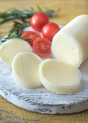 Sliced Formaggio with tomatoes and rosemary on the wooden board