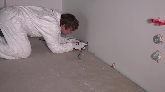 male electrician worker hands at wiring cable or wall outlet socket installation