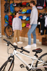 Obraz premium close-up view of new bicycle and father with son standing behind in bike shop