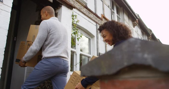 4K Happy mixed race couple moving house, carrying boxes into new home