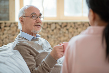 Tea time. Attractive pleasant senior man talking while posing on blurred background and enjoying life