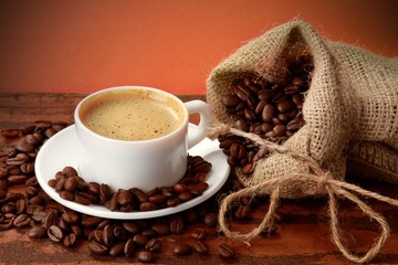 Cup of coffee surrounded by coffee beans
