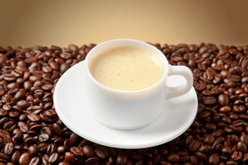 Cup of coffee surrounded by coffee beans