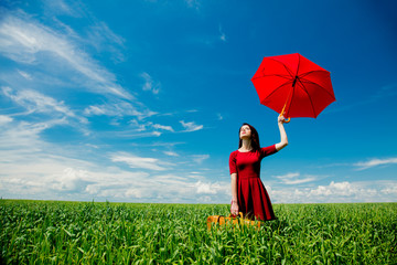 girl with suitcase and umbrella at wheat field