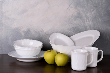 White dishware stacked on a wooden table against grey background on wooden table