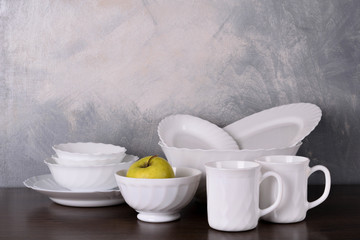 White dishware stacked on a wooden table against grey background on wooden table
