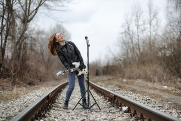  A rock musician girl in a leather jacket with a guitar 