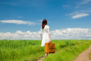 girl with suitcase at wheat field