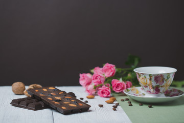 Obraz na płótnie Canvas handmade chocolate bar filled with different berries and nuts, cup of tea with mint is on a flat surface of the linen and old wooden table cracked paint