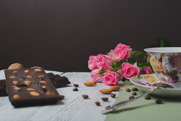 handmade chocolate bar filled with different berries and nuts, cup of tea with mint is on a flat surface of the linen and old wooden table  cracked paint