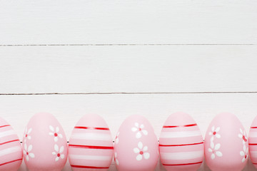 Pink hand painted Easter eggs on white wooden background