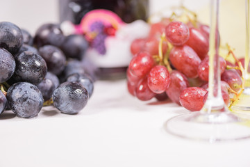 Fresh grape and red wine on the white table with two glasses, selective focus