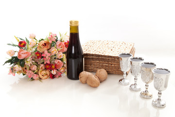 Naklejka premium passover elements on studio shite background, matzoh, wine, goblets, walnuts