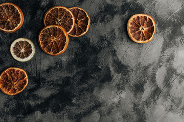 Slices of dry oranges on dark stone table