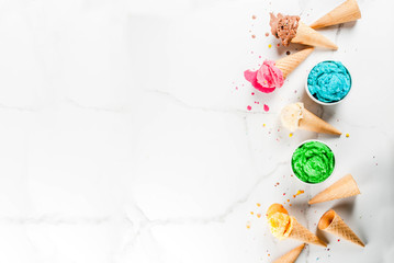 Different homemade melting ice cream in bowls and waffle ice cream cones, white vanilla, orange, pink berry, green, blue, chocolate white marble background  copy space top view