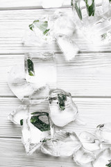 Flat lay of ice cubes with frozen aloe inside on white wooden table