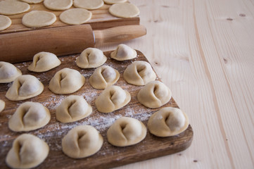 Fototapeta na wymiar Raw Homemade dumplings with meat on the wood table, Russian Pelmeni
