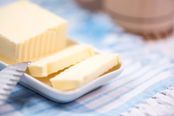 Piece of butter on plate with knife. Background and shallow focus.
