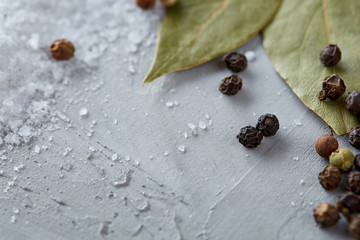 Composition of bay laurel leaf with peppercorn and salt isolated on dark background, top view, close-up, selective focus