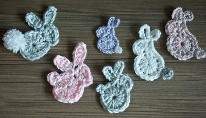 Easter decoration, cute bunny rabbits, crochet application made of soft yarn in pastel colors, wooden texture background. Homemade decor. Top view, shallow depth of focus. Spring, Easter holidays.