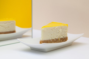 One piece of lemon cheesecake on a white  plate.