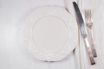Empty plate and fork and knife on wooden texture background