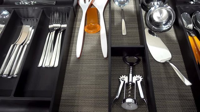 4K view of spoons, forks and other cutlery in a modern cutlery box drawer.    