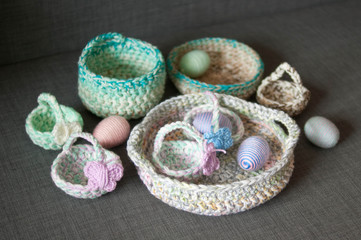 Easter decoration, crochet basket, striped colorful egg wrapped in soft yarn thread, pastel colors, butterfly, dark grey texture background. Homemade decor. Shallow depth of focus. Easter holidays.