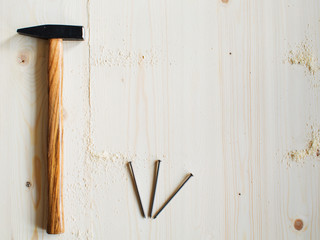 A hammer, nails and sawdust on a wooden surface are ready for use
