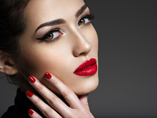 Beautiful woman with bright make-up and red nails.