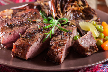 Slices of beef steak served with baked artichoke