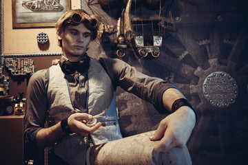 Portrait of a young mad scientist traveler in a steampunk style suit with a card.