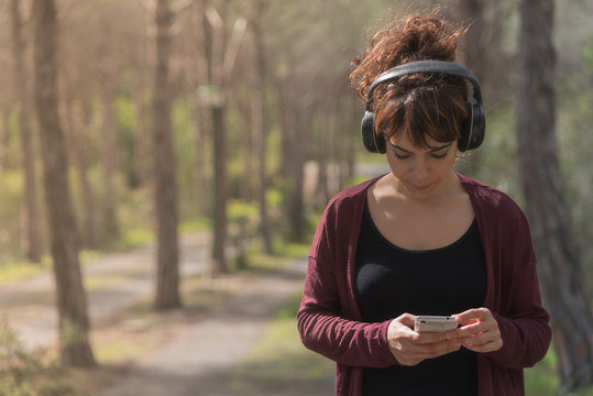 Donna sola usa smartphone nel bosco