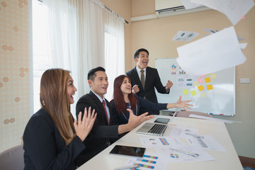 A group Asian of business men and women who  glad happy succeeded in business. with a laptop at office desk and document. business success concept.