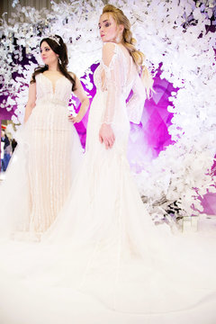 Two models in the image of a bride in the background of a violet decor