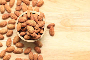 Almond in a bowl on wooden background with copy space