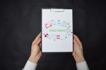 In the hands of a businessman a notebook with the inscription:FOREX TRADING