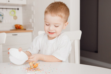 Children sprinkle cupcakes with colored caramel for Easter and eat.