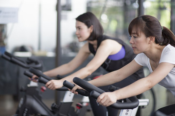 Fototapeta na wymiar Close-up footage of a women working out in gym on the exercise bike, young woman cycling in the gym. female exercising in fitness gym for good health.