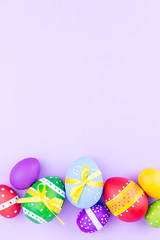 Fototapeta na wymiar Colorful easter eggs on pastel purple background flat lay. Copy space