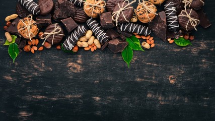 Set of chocolate with nuts, cookies and cocoa. On a black wooden background. Top view. Copy space for text.