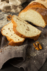 Fresh bread on a gray linen napkin and wrapped in kraft paper. Sliced loaf. Sprinkled with flour and sesame.