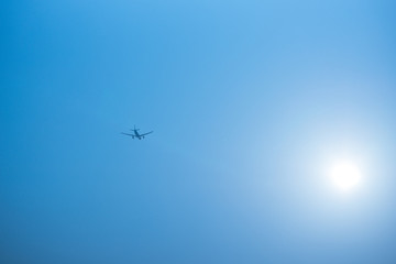 Airplane flying in the blue sky among clouds and sunlight