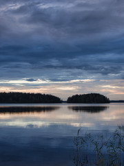 Landscape shot with a lake,clouds islands and some waterplants.